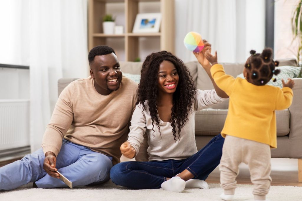Stone Oak Counselors Home 23 A happy and relaxed African American mom and dad playing with their toddler girl on the floor